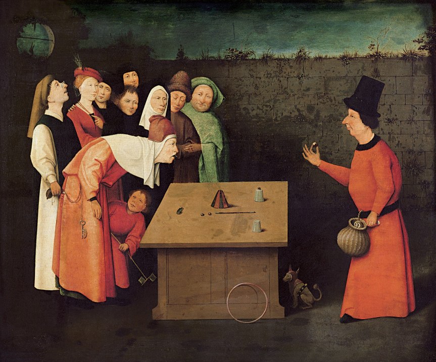 A group of spectators watches a street performer at a table, displaying tricks with cups and balls, while a dog observes nearby.